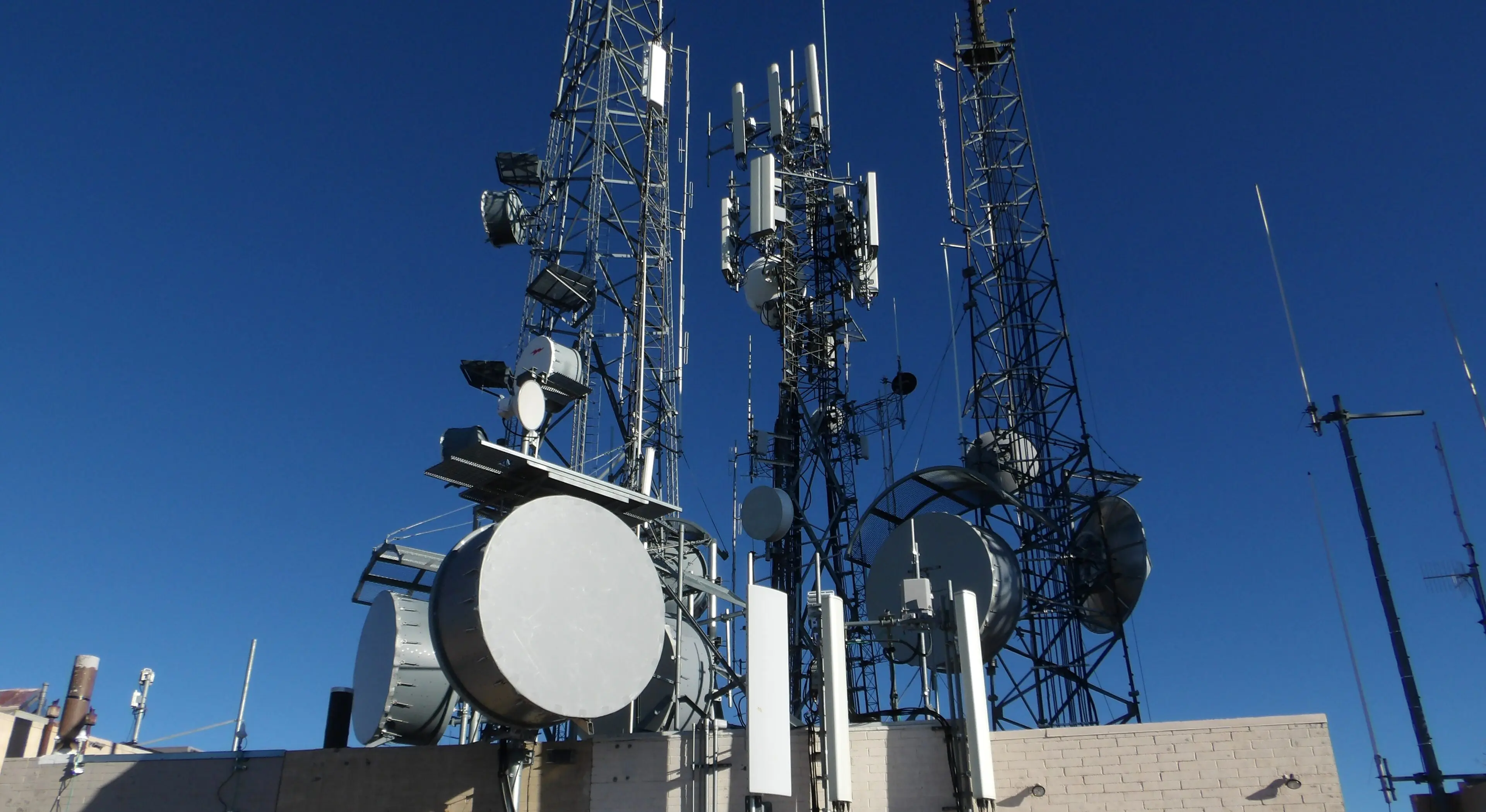 MINOLTA DIGITAL STILL CAMERA A group of cellular antennas sitting on top of a building.
